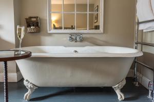 a white bath tub in a bathroom with a mirror at Lord Crewe Arms Blanchland in Blanchland +57 photos