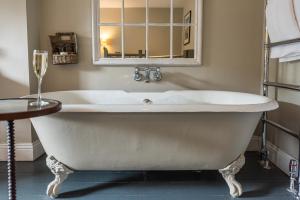 uma banheira branca na casa de banho com um espelho em Lord Crewe Arms Blanchland em Blanchland