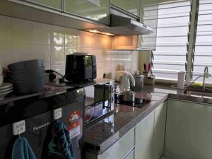 cocina con encimera y microondas en Comfy Beachfront View at Seri Bulan Condominium Teluk Kemang Beach en Port Dickson