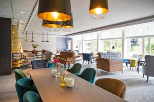 een wachtkamer met tafels, stoelen en ramen bij Bilderberg Hotel 't Speulderbos in Garderen
