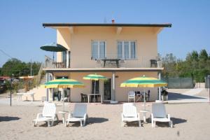 a group of chairs and umbrellas on a beach at Villa Serena in Rosolina Mare
