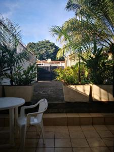 un patio con mesa, sillas y palmeras en Joli jardin en ville en Yaundé