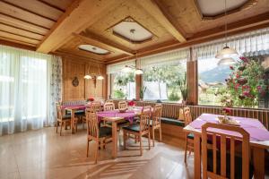 un comedor con mesas y sillas y una gran ventana en Pension Garni Appartement Ortner, en Sankt Johann in Tirol