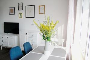 una mesa de comedor con un jarrón de flores. en Apartament Flauta, en Mikołajki
