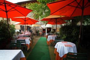 a row of tables and chairs with red umbrellas at AL BORGO ANTICO Ristorante con camere in bedizzol