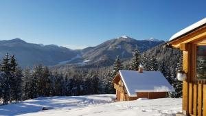 a snow covered cabin with mountains in the background at Agriturismo Gacceman in Ugovizza
