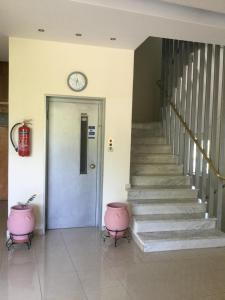 a hallway with a clock on the wall and stairs at Hotel Kallithea in Loutra Edipsou