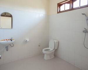 a white bathroom with a toilet and a sink at Batu Jaran Hill Cottage Uluwatu in Uluwatu