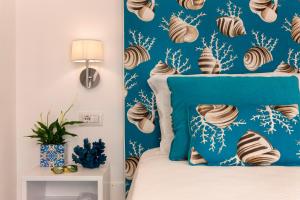 a bedroom with a bed with a blue headboard and seashell wallpaper at Gala Residence Villa Giovanna in Ravello