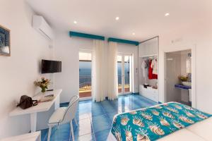 a bedroom with a bed and a desk and a balcony at Gala Residence Villa Giovanna in Ravello