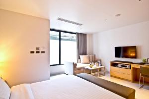 a hotel room with a bed and a television at Dune Hua Hin Hotel in Hua Hin