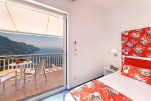 a bedroom with a balcony with a bed and a table at Gala Residence Villa Giovanna in Ravello
