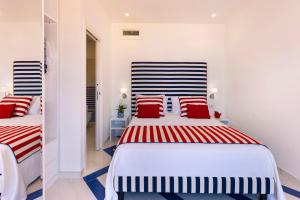 two beds in a white room with red and blue pillows at Gala Residence Villa Giovanna in Ravello