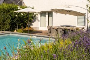 a pool with a table and an umbrella next to a house at B&B Hostellerie Marie in Eben-Emael
