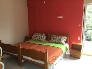 a bedroom with a wooden bed with a red wall at Hotel Kallithea in Loutra Edipsou