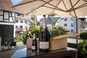 twee flessen wijn op een tafel met een paraplu bij Hotel Kaiserhof in Medebach