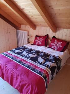 a bed in a wooden cabin with red pillows at Agriturismo Gacceman in Ugovizza