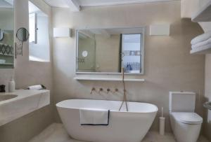 a white bathroom with a tub and a toilet at Xinara House in Tripótamos