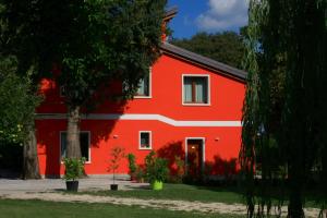 a red building with a tree in front of it at Agriturismo Ca' La Pergola in Verona