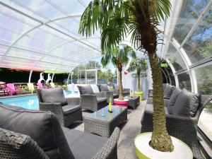 a conservatory with chairs and palm trees and a pool at Pleasant Holiday Home with Sauna and Jacuzzi in Courtil in Gouvy