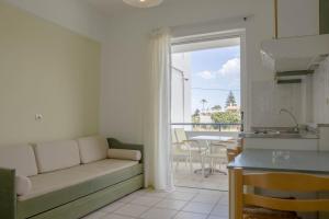 ein Wohnzimmer mit Sofa und eine Küche in der Unterkunft Pinelopi Hotel in Platanes