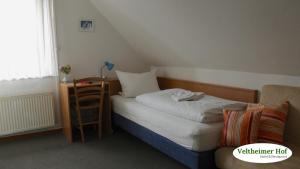 a small bedroom with a bed and a table at Landgasthaus Veltheimer Hof in Porta Westfalica
