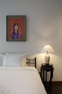 1 dormitorio con 1 cama y una pintura en la pared en Centraltique Downtown - Bespoke Colonial House Near Hoan Kiem Lake en Hanoi