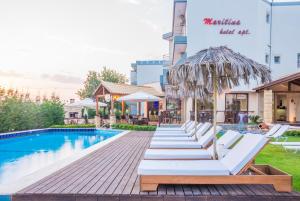 a row of white lounge chairs next to a swimming pool at Maritina Apartments in Ixia