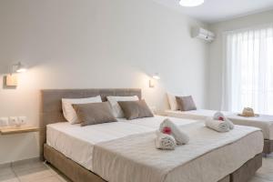 two beds with towels on them in a bedroom at Pinelopi Hotel in Platanes