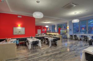 un ristorante con tavoli, sedie e una parete rossa di Hotel Firenze a Bibione