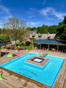 une piscine avec une terrasse et une maison dans l'établissement Le Petit Moulin du Rouvre, à Saint-Pierre-de-Plesguen