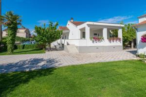 a white house with a lawn in front of it at Apartments Coronata in Biograd na Moru