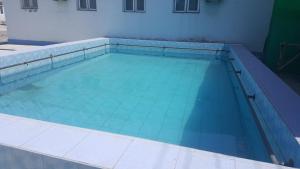 a swimming pool with blue water in front of a building at Dangara Hotel in Kokand