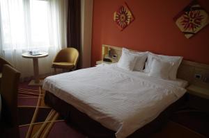 a hotel room with a large bed with white sheets at Mari Vila Hotel in Bucharest