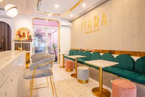 Isara Boutique Hotel and Cafe في فوكيت تاون: وجود بار وكراسي خضراء وطاولات في الغرفة