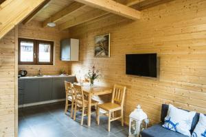 a kitchen and dining room with a table and a tv at Domki ALEX przy plaży in Dziwnówek