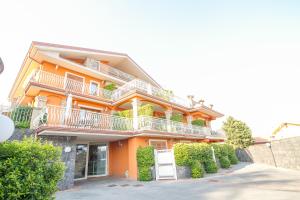 特雷卡斯塔尼埃特纳帝景公寓式酒店的橙色的房子,设有白色的阳台和灌木丛