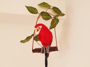a red bird sitting on a plant holder at Parrot’s House in Lloret de Mar