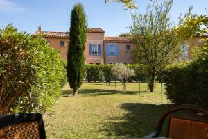 une grande maison avec des arbres et un banc dans une cour dans l'établissement SOWELL RESIDENCES Les Mazets, à Arles