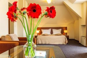 a vase with red flowers on a table in a bedroom at Sofia Place Hotel by HMG in Sofia +123 photos