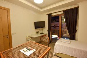 フェティエにあるLidya City Hotelのベッド、テーブル、テレビが備わるホテルルームです。