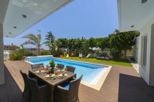 a patio with a table and chairs next to a swimming pool at Larnaca Villa Marisol Kiti in Larnaka
