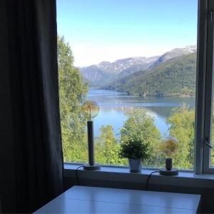 a window with a view of a lake and mountains at Studioleilighet i Haukedalen in Holsen