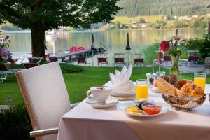 a table with breakfast food and a view of a lake at Hotel Seewinkel in Fuschl am See