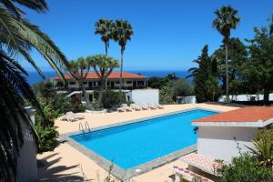 una piscina con palmeras y una casa en Apartamentos Miranda en Breña Alta