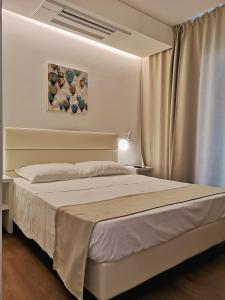 1 dormitorio con 1 cama y una pintura en la pared en Family Suite Appartments Orchidea Blu, en Rímini