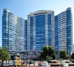 un grand bâtiment bleu avec des voitures dans un parking dans l'établissement Greendoor Arcadia, à Odessa