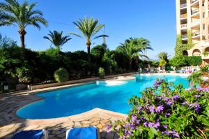 una piscina con palmeras y un edificio en Residhotel Villa Maupassant en Cannes