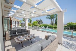 a patio with couches and a table and a pool at Oscar Domain Villa in Protaras