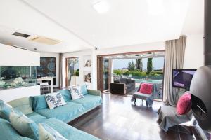 ein Wohnzimmer mit blauen Sofas und einem TV in der Unterkunft Oscar Domain Villa in Protaras